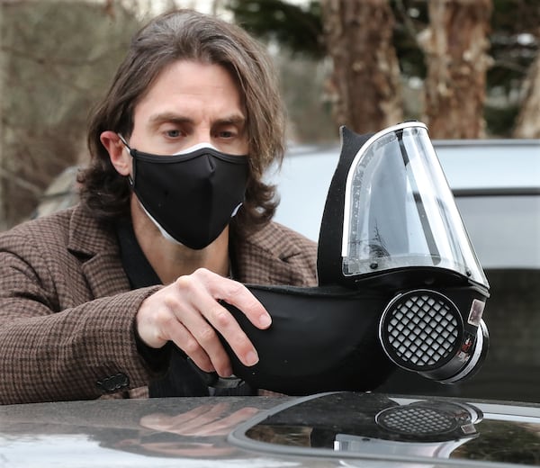 Ryan Proffitt, a 39-year-old language arts teacher at Lanier High School in Gwinnett who is suffering from long-term effects of COVID-19, removes his N-95 battery powered respirator he wears in the classroom and in public after arriving home from school on Feb.1, 2021, in Sugar Hill.  (Curtis Compton / Curtis.Compton@ajc.com)