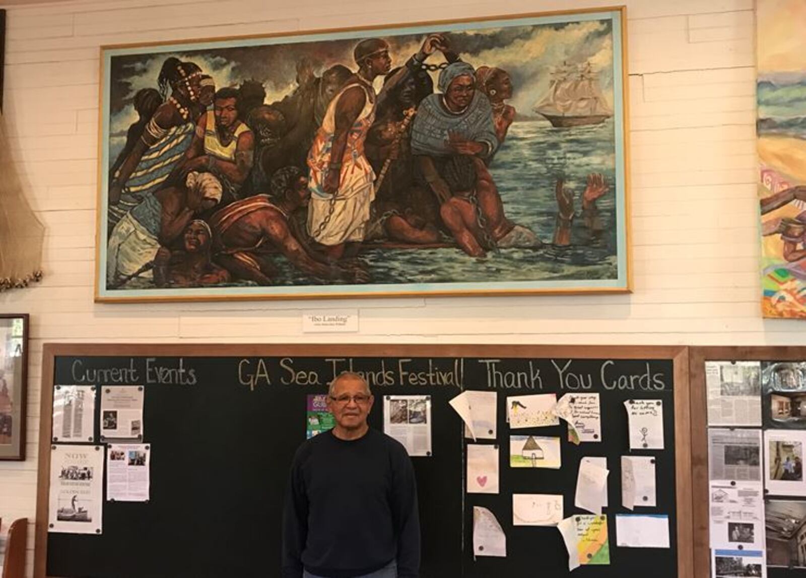 Emory Rooks, manager of the Historic Harrington School and Cultural Center, stands before the painting  depicting Igbo (or Ibo) Landing  by artist Diane "Dee" Williams.