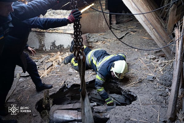 In this photo provided by the Ukrainian Emergency Service, emergency services personnel remove part of a Russian missile that hit an apartment house during massive missile attack in Kyiv, Ukraine, Sunday, Nov. 17, 2024. (Ukrainian Emergency Service via AP)