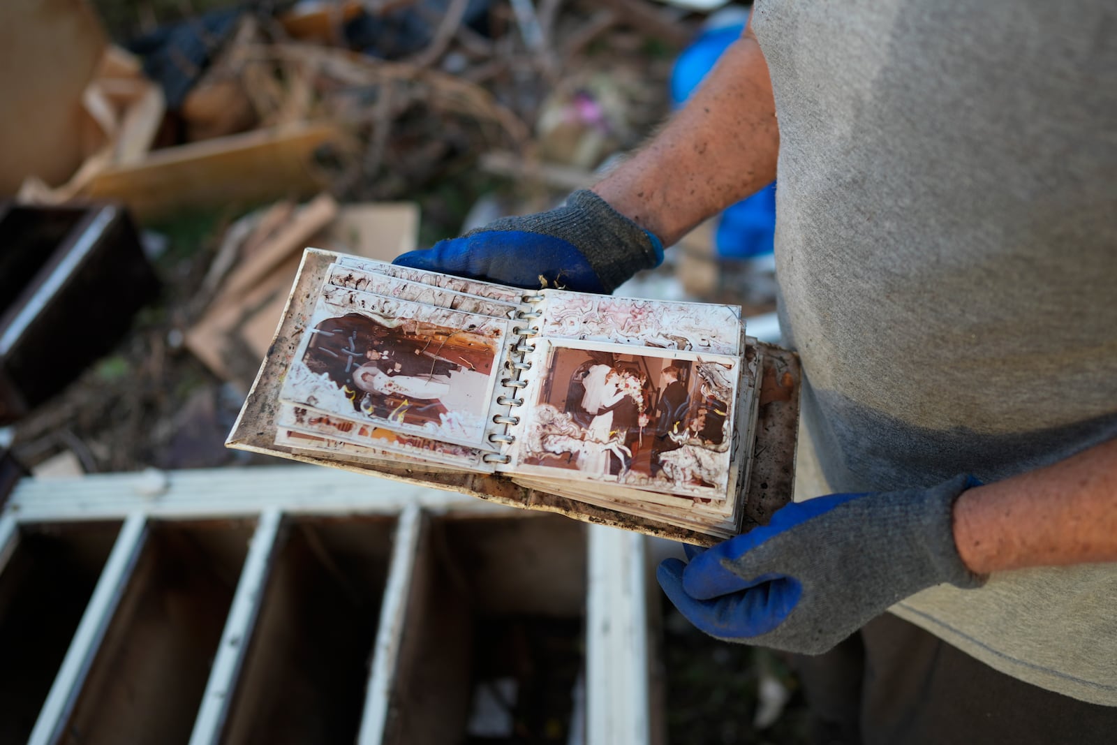 Robert Turick, 68, finds a water-damaged album of wedding photos in the debris from other homes swept into his yard by Hurricane Milton storm surge, in Englewood, Fla., Friday, Oct. 11, 2024. (AP Photo/Rebecca Blackwell)