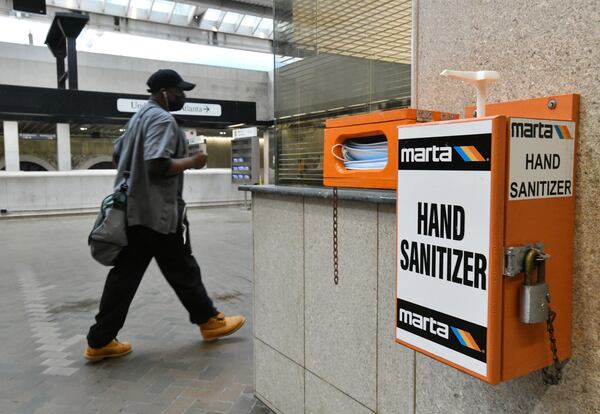 In this file photo, A MARTA rider walks past mask and hand sanitizer dispensers at the Five Points MARTA station. (Hyosub Shin / Hyosub.Shin@ajc.com)