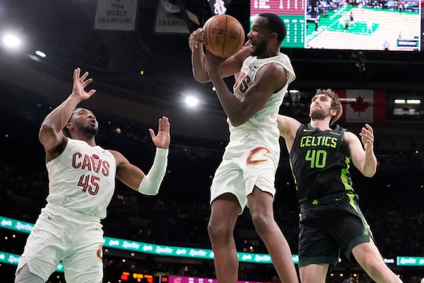 Cleveland Cavaliers forward Evan Mobley, center, grabs a rebound against Boston Celtics center Luke Kornet (40), as Cavaliers' Donovan Mitchell (45) looks on during the second half of an NBA basketball game, Friday, Feb. 28, 2025, in Boston. (AP Photo/Charles Krupa)