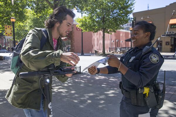 Atlanta Police Officer Ayesha Abdul-Hakeem stops Georgia State University student Ned Degenhard during her foot patrol in Atlanta’s Midtown community. Degenhard was riding on the sidewalk when he was waved down by Officer Abdul-Hakeem and given a pamphlet that explains the dos and don’ts of riding e-scooters in the city. (Alyssa Pointer/Atlanta Journal Constitution)