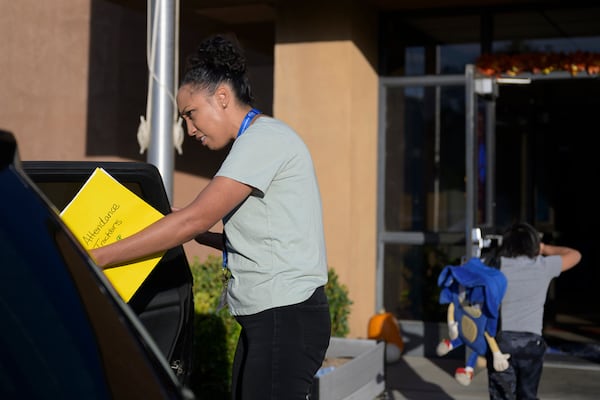 Attendance Clerk Katrice Grant looks to help a student get out a a car as he is dropped off at school, Tuesday, Oct. 1, 2024, at Algodones Elementary School in Algodones, N.M. (AP Photo/Roberto E. Rosales)