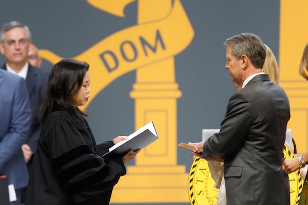 Gov. Brian Kemp, right, is sworn in for his second term by Justice Carla Wong McMillian in an inauguration ceremony Thursday at Georgia State University's Convocation Center. Kemp used the event to stress that “government should care a lot more about safe streets, good schools, and good-paying jobs than what the pundits are saying on cable news.” (Natrice Miller/natrice.miller@ajc.com)  