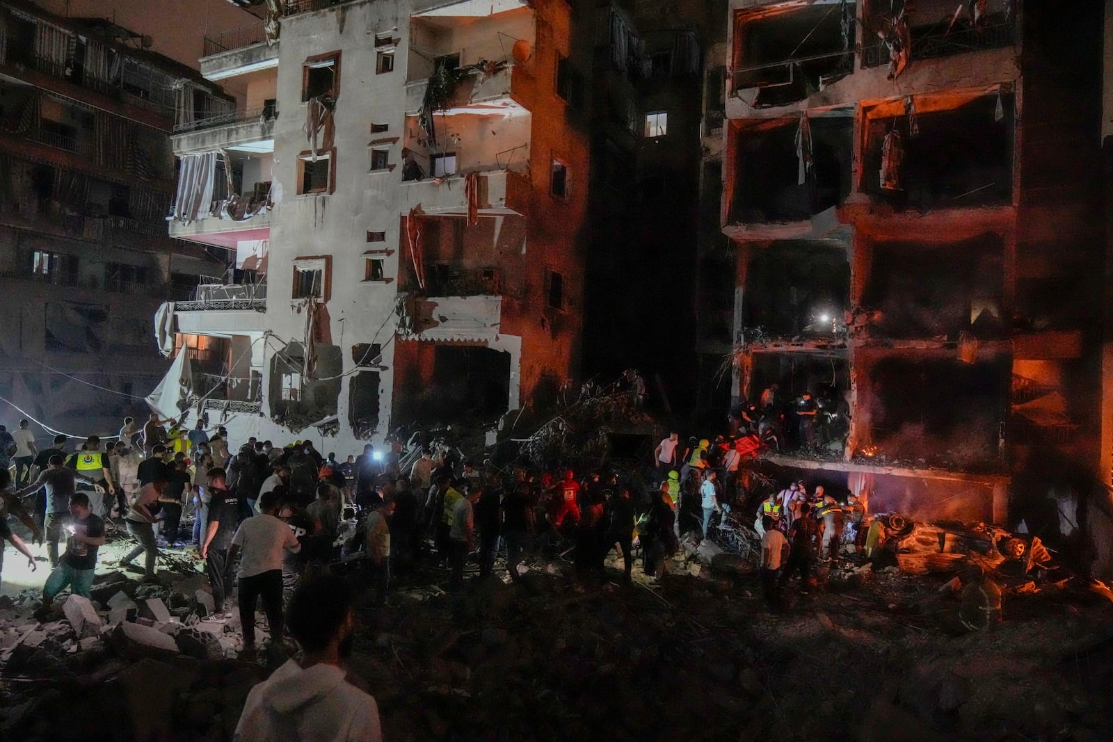 People gather in front of destroyed buildings hit by an Israeli airstrike in central Beirut, Lebanon, Thursday, Oct. 10, 2024. (AP Photo/Bilal Hussein)