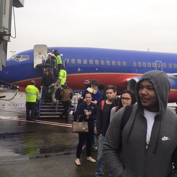 Passengers disembark from Southwest Airlines Flight 3392 from New Orleans on Sunday. The plane landed at 1:31 p.m. Sunday, Dec. 17, 2017, at Hartsfield-Jackson International Airport, but passengers sat on the plane for more than two hours because of a massive power outage that ensued just before their arrival. Airline personnel brought a ladder to the tarmac. (Photo by Rick Crotts / AJC)