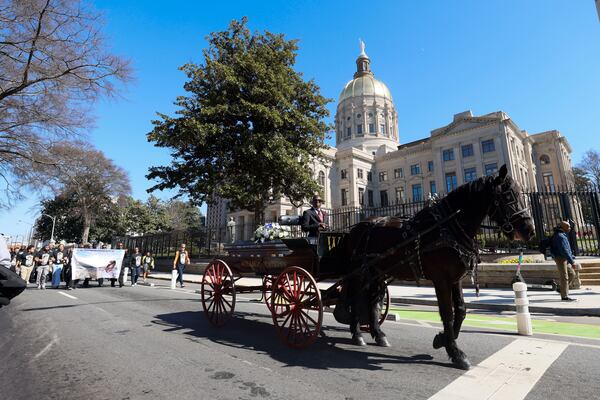 A horse-drawn carriage carries the remains of Cornelius Taylor from Ebenezer Baptist Church to Atlanta City Hall on Monday.