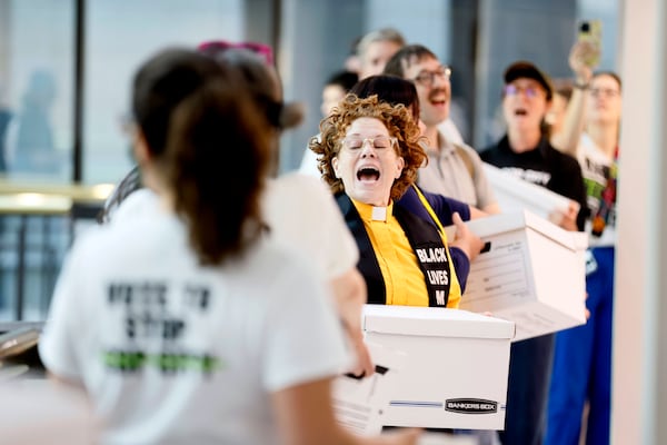 Opponents of the Atlanta public safety training center chant as they carry boxes of petition signatures into City Hall in 2023.