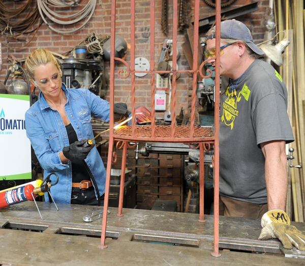 Nicole Curtis, host of HGTV’s “Rehab Addict,” uses a blowtorch during a recent trade show demo. She says she often tells prospective homeowners that “there’s a difference between renovation and restoration … if you have old, stick with the old. Don’t replace old with a new-old style.” 