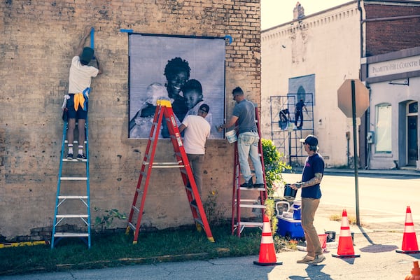 Volunteers work on installation of one of the 14 black-and-white murals of Palmetto citizens that have gone up recently at nine locations around town. Courtesy of Andrew Hetherington