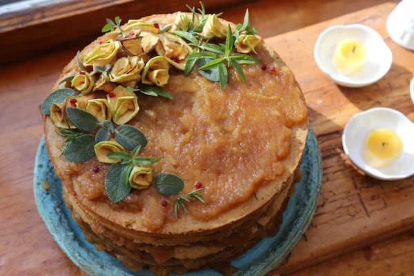 An apple stack cake is a traditional Appalachian dessert featuring a thick dried apple filling spread between layers of sorghum-sweetened cake. Once stacked, the cake is left to cure for a few days before being eaten. Some apple stack cakes are topped with confectioners’ sugar. This cake, prepared by Barbara Swell, Ashley Capps, Ashley English and Susannah Gebhart, is decorated with dried apples shaped like roses, lemon verbena, sage, rosemary and raspberries. TYSON HORNE / TYSON.HORNE@AJC.COM