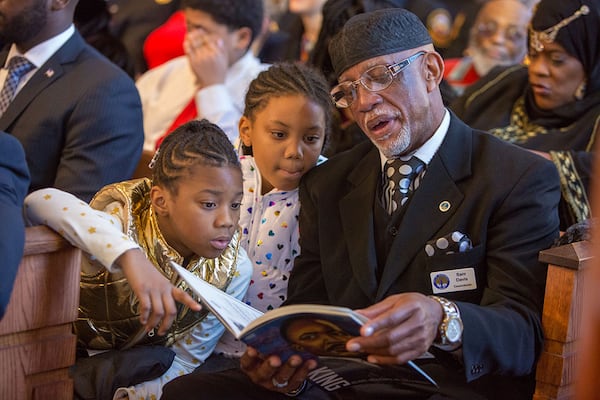 Qeristin Warnick (left) and her sister Makayla looked at the program with their grand father Councilman Sam Davis during the Martin Luther King, Jr. Annual Ecumenical Commemorative Service at Ebenezer Baptist Church located near The King Center in Atlanta on January 15th, 2018. The theme of the 2018 Observance was 'King:His Voice, His Teachings and His Love for Humanity. The Keynote Speaker was Dr. Bernice A. King - CEO, The King Center. (Photo by Phil Skinner)