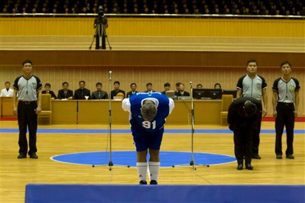 Dennis Rodman bows to North Korean leader Kim Jong Un, seated above in the stands, before an exhibition basketball game with U.S. and North Korean players at an indoor stadium in Pyongyang, North Korea on Wednesday, Jan. 8, 2014. (AP Photo/Kim Kwang Hyon)