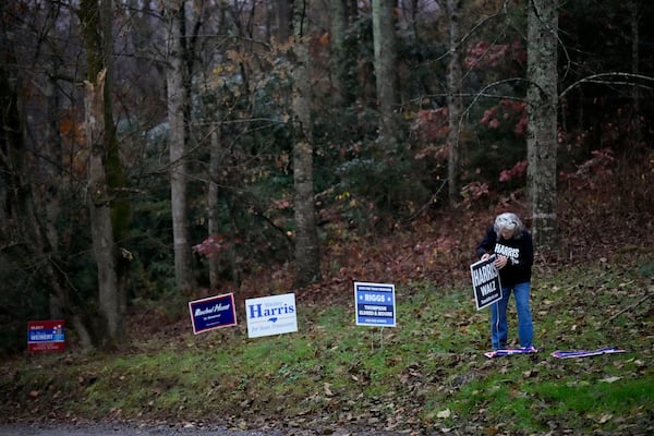 A campaign worker posts a Harris-Walz sign near a polling place, Tuesday, Nov. 5, 2024, in Black Mountain, N.C. (AP Photo/George Walker IV)