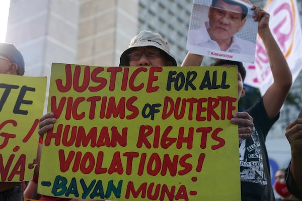 People hold signs against former Philippine President Rodrigo Duterte following his arrest in Quezon City, Philippines, Tuesday, March 11, 2025. (AP Photo/Basilio Sepe)