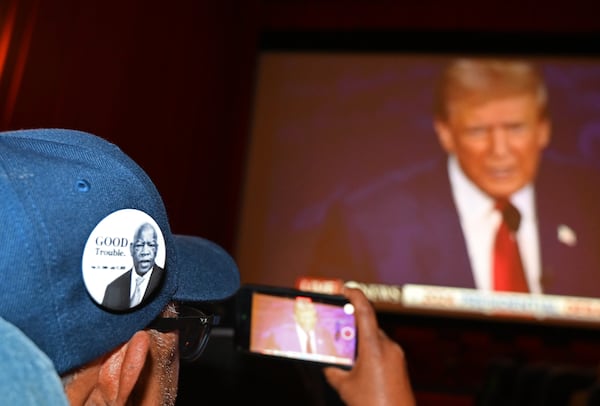 A supporter wearing a John Lewis pin takes a video as he watches the presidential debate between Republican presidential nominee former President Donald Trump and Democratic presidential nominee Vice President Kamala Harris during a Democrat Debate watch party at Tara Theater on Tuesday, Sept. 10, 2024, in Atlanta. The ABC News debate, which begins at 9 p.m., is expected to be the only chance for voters to see the two rivals in a side-by-side confrontation this election season. (Hyosub Shin/AJC)