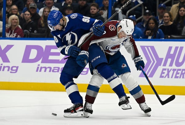 Tampa Bay Lightning defenseman J.J. Moser (90) and Colorado Avalanche center Nathan MacKinnon (29) battle for the puck during the first period of an NHL hockey game Monday, Nov. 25, 2024, in Tampa, Fla. (AP Photo/Jason Behnken)