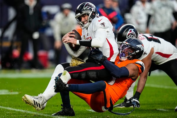 Falcons quarterback Kirk Cousins takes a sack from Broncos linebacker Nik Bonitto.