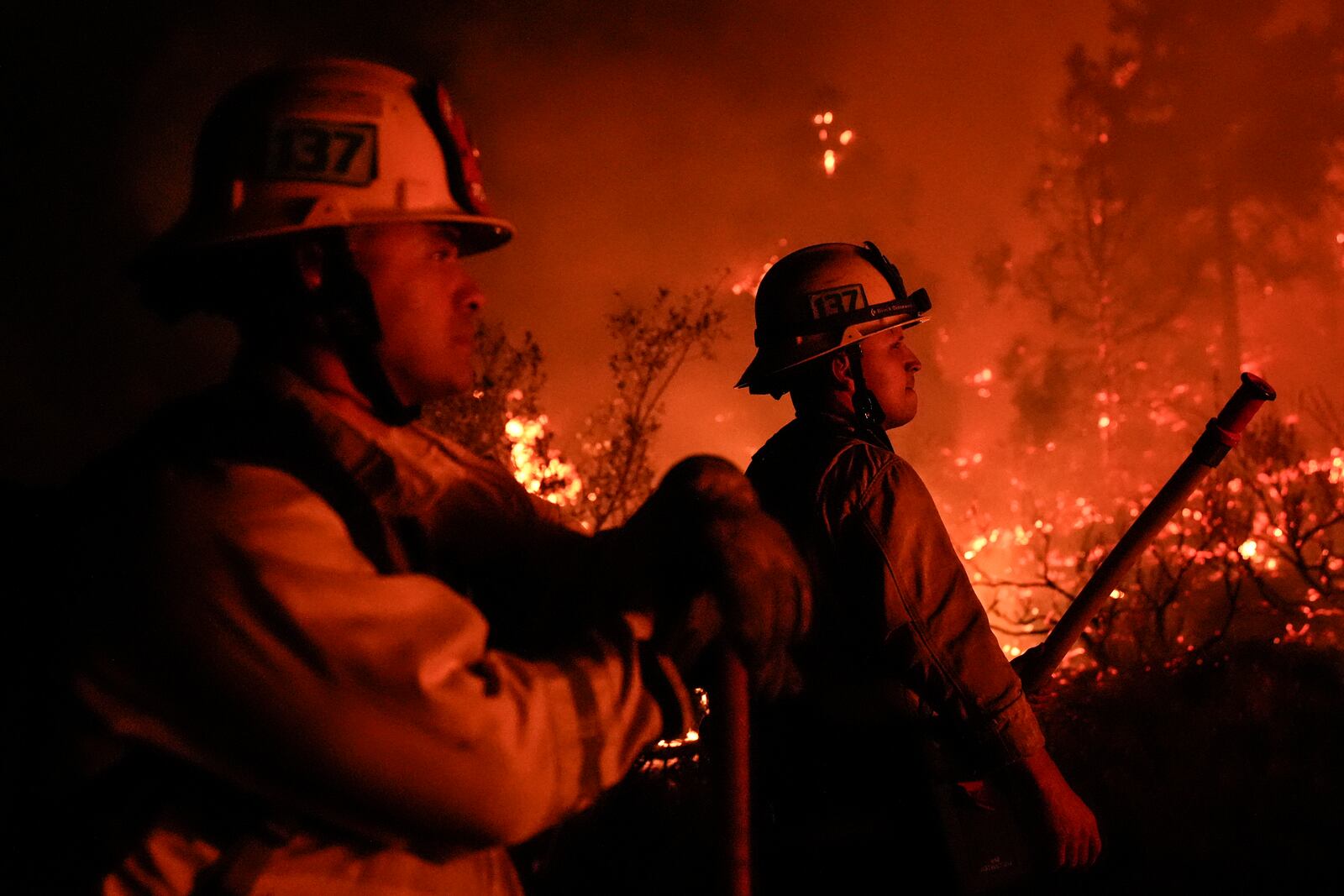 Firefighters are illuminated by the glow of the Bridge Fire in Wrightwood, Calif., Tuesday, Sept. 10, 2024. (AP Photo/Jae C. Hong)