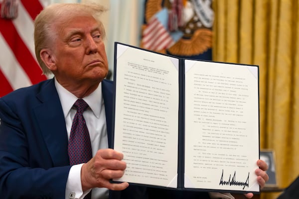 President Donald Trump holds up a signed executive order aiming to declassify remaining federal records relating to the assassinations of President John F. Kennedy, Sen. Robert F. Kennedy, and Martin Luther King Jr., in the Oval Office of the White House, Thursday, Jan. 23, 2025, in Washington. (AP Photo/Ben Curtis)