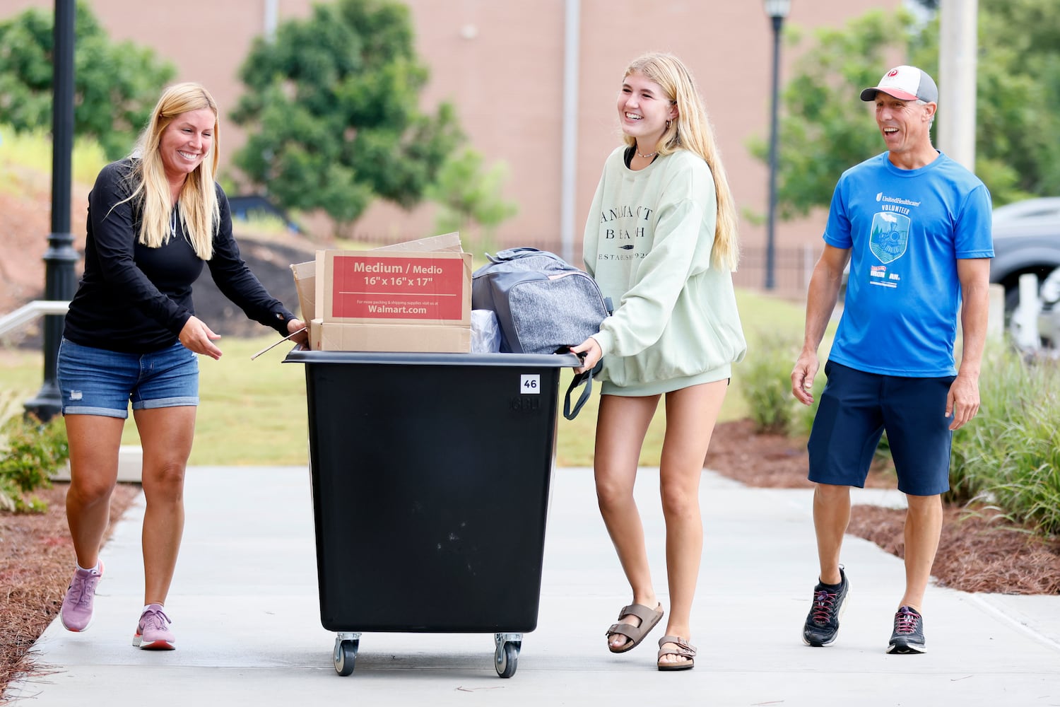 Madison Fadely  (center) pushes a cart full of her stuff with her mom Joanne Fadely while her dad Jason Fadely watches; they walk into the new building at Kennesaw State University campus. The Summit will house the 500 first-year students. (Miguel Martinez / miguel.martinezjimenez@ajc.com)