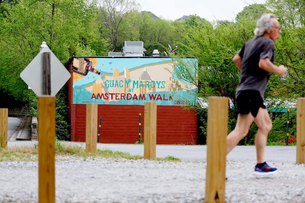 A person jogs by the Beltline across from Amsterdam Walk shopping center on Tuesday, April 4, 2023.  Portman Holdings is pursuing a plan to redevelop Amsterdam Walk, a 9-acre shopping center along the Beltline and Piedmont Park.   Miguel Martinez / miguel.martinezjimenez@ajc.com