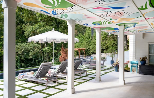 Gina Sims and her team enclosed the deck behind the house, allowing her to create a covered patio area underneath it. Adding some color to the space, Sims painted 12 eight-by-four panels of plywood that were then affixed to the ceiling. (Courtesy of Cati Teague)