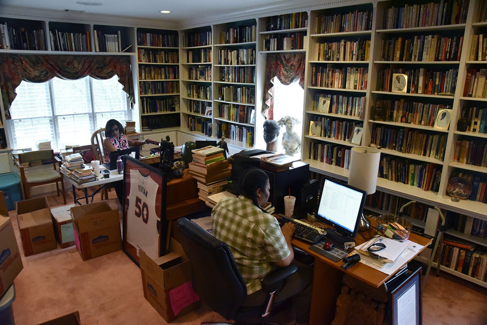 C.T. Vivian's daughter Charisse Thornton (background) and Dawnn Mitchell work on checking inventory in C.T. Vivian's home library on Tuesday, July 25, 2017. The new library will be housed in the new Cook Park in Vine City. Vivian lived in the same Vine City neighborhood that will border Cook Park where his library is to be constructed under a 101-foot Peace Column. The 6,000 volume C.T. Vivian Library is one of the most impressive private collections in the city. HYOSUB SHIN / HSHIN@AJC.COM