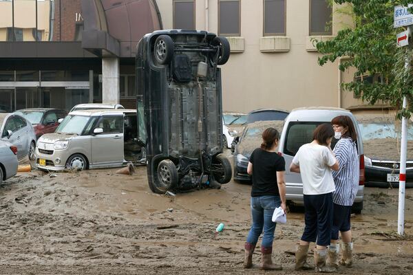 A car stands vertically on a muddy road after being washed away by flood. 