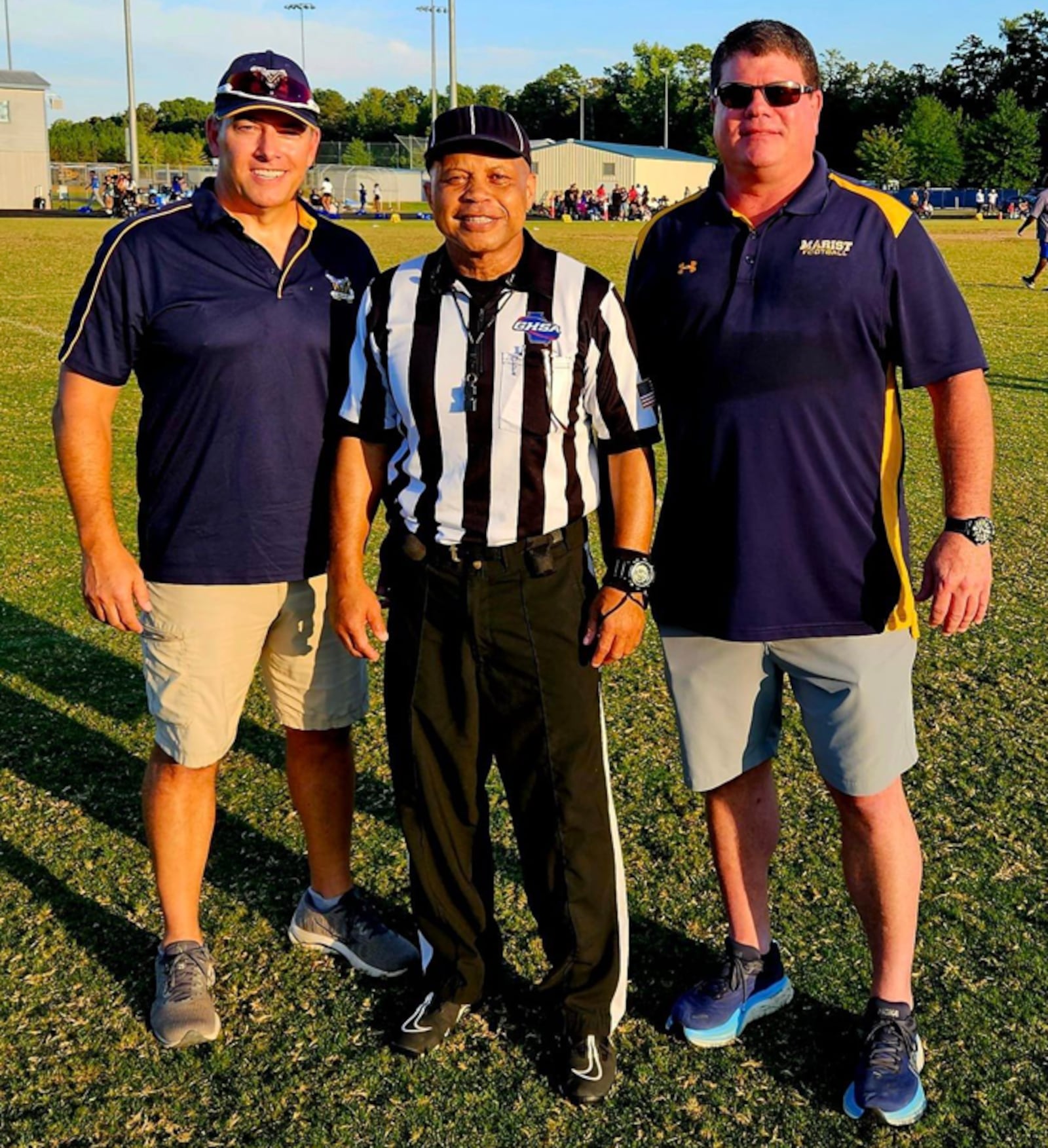 Jerry Mays, in his officials uniform, stands with Eric Maurer (left) and Charlie Greene. The three played in the Class 3A championship game of 1984, when Mays' Thomson team defeated Maurer's and Greene's Marist team 27-17.  They met again when the Marist graduates, who have sons on Marist's ninth-grade football team, discovered Mays officiating a game in Covington in September. It led to a nostalgic reunion.