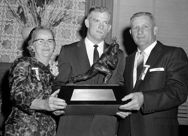 FILE - John Crow, Texas A&M halfback, center, and his parents, Mr. and Mrs. Harry Crow, of Springhill, La., hold the Heisman Memorial Trophy awarded to John as the outstanding college football player of 1957 at dinner at the Downtown Athletic Club in New York, Dec. 12, 1957. (AP Photo/File)