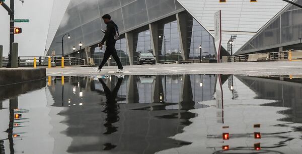 Quarnadius Wood steers clear of a puddle at the intersection of Martin Luther King Jr. Drive and Centennial Olympic Park Drive, where Taylor Swift fans will flock Friday night for the first of the pop icon's three sold-out shows at Mercedes-Benz Stadium.