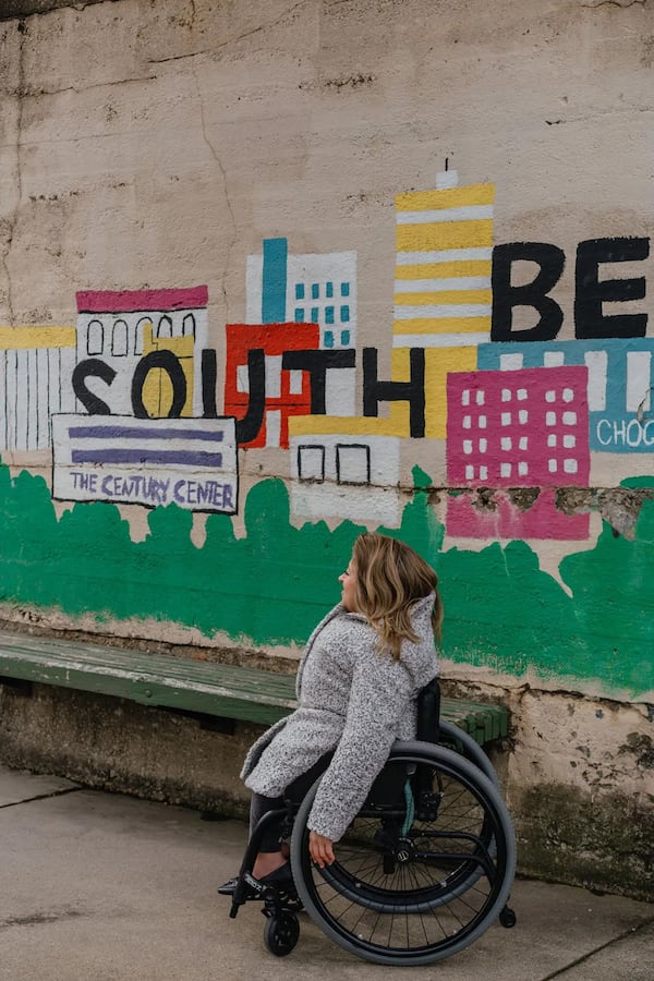 Emily Voorde sits for a portrait near the riverwalk of the Saint Jospeh River in South Bend, Indiana. (Photo Courtesy of Jamie Kelter Davis, The 19th)