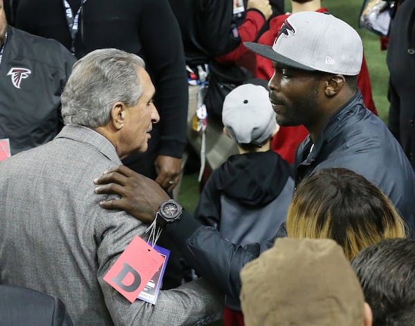 Former Falcons quarterback Michael Vick and owner Arthur Blank greet each other on the sidelines before the Falcons play the Saints on Sunday, Jan. 1, 2017, in Atlanta. 