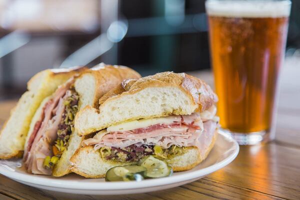 Chef Rob Philip serves up a muffuletta with ham, mortadella, soppressata, provolone, and olive salad. Photo Credit: Tomas Espinoza