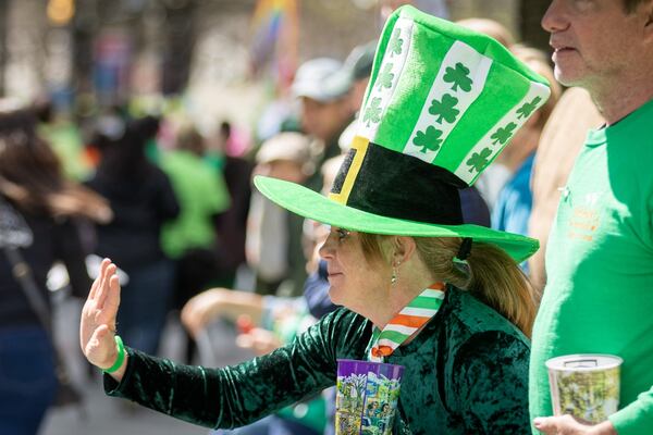 Kathy Workman waves as the Atlanta St. Patrick's Parade heads down Peachtree Street in 2023. (Steve Schaefer/steve.schaefer@ajc.com)