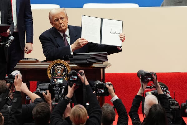 President Donald Trump holds up an executive orders after signing it at an indoor Presidential Inauguration parade event in Washington, Monday, Jan. 20, 2025. (AP Photo/Matt Rourke