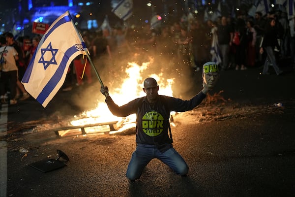 FILE - A protester holds an Israeli flag as Israelis light a bonfire during a protest after Prime Minister Benjamin Netanyahu has dismissed his Defense Minister Yoav Gallant in a surprise announcement in Tel Aviv, Israel, Tuesday, Nov. 5, 2024. (AP Photo/Francisco Seco, File)