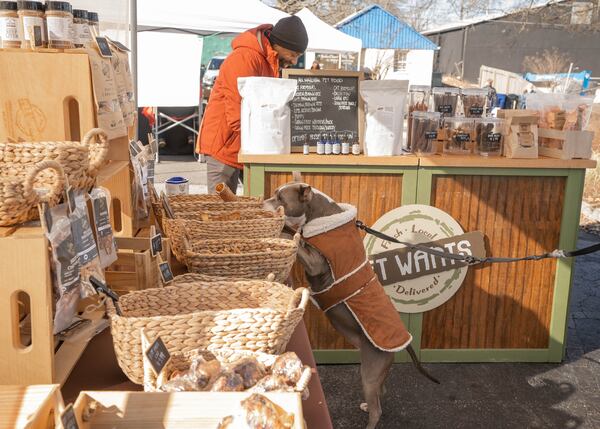 Somepuppy is curious about what's in the basket at the Pet Wants booth at the Avondale Estates Farmers Market as Benjamin King tends to business.