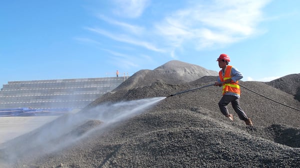 FILE- A Vietnamese worker sprays water over stones to be used in the construction of a silo for storing soil contaminated with Agent Orange dioxide at the site of a former American airbase in Danang, Vietnam on April 24, 2013. (AP Photo/Hau Dinh)