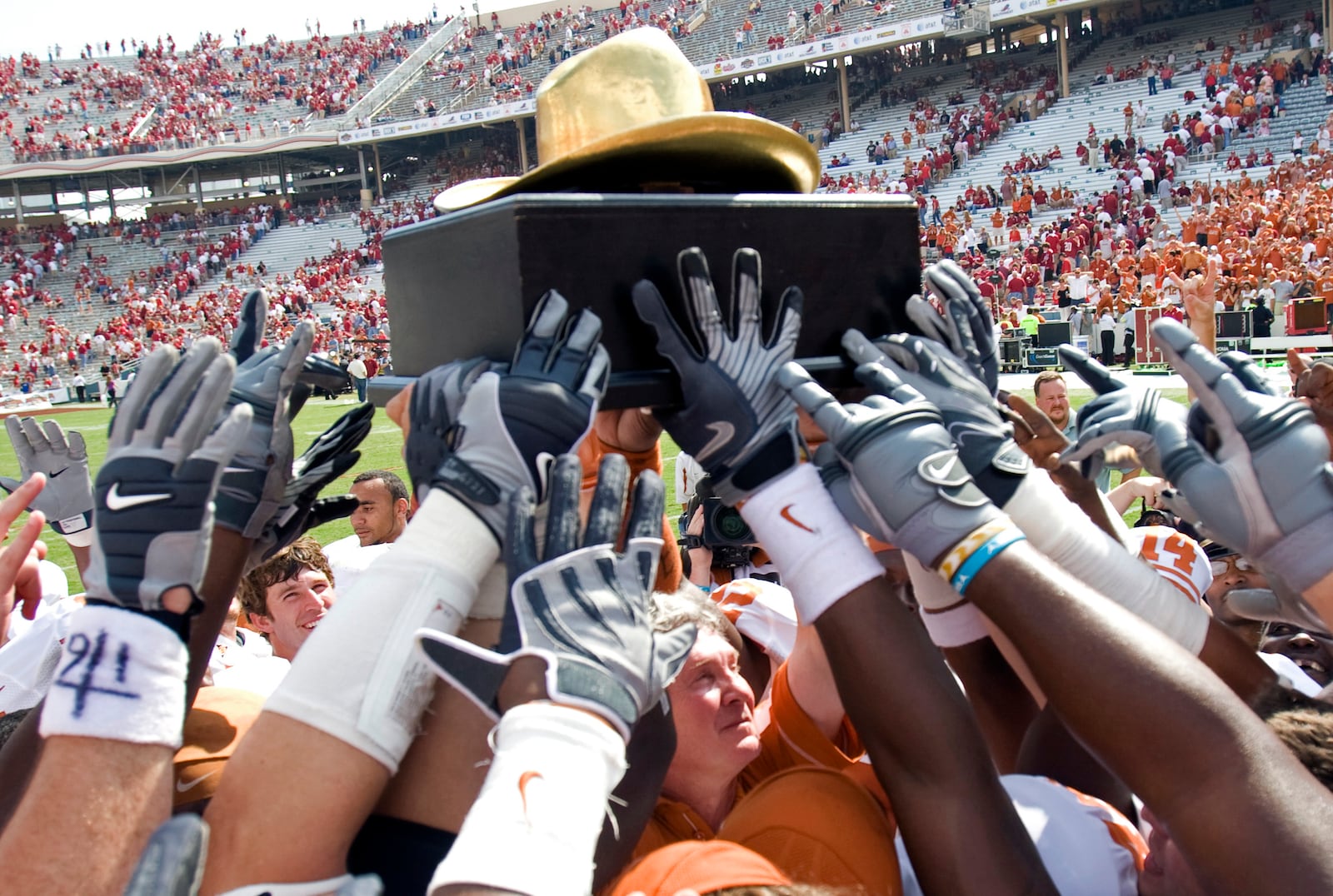 FILE - In this Oct. 11, 2008, file photo, Texas coach Mack Brown, center under trophy, and the Longhorns celebrate their 45-35 win over Oklahoma win with the "Golden Hat Trophy" after an NCAA college football game in Dallas. (AP Photo/ University of Texas, Jim Sigmon, Pool, File)