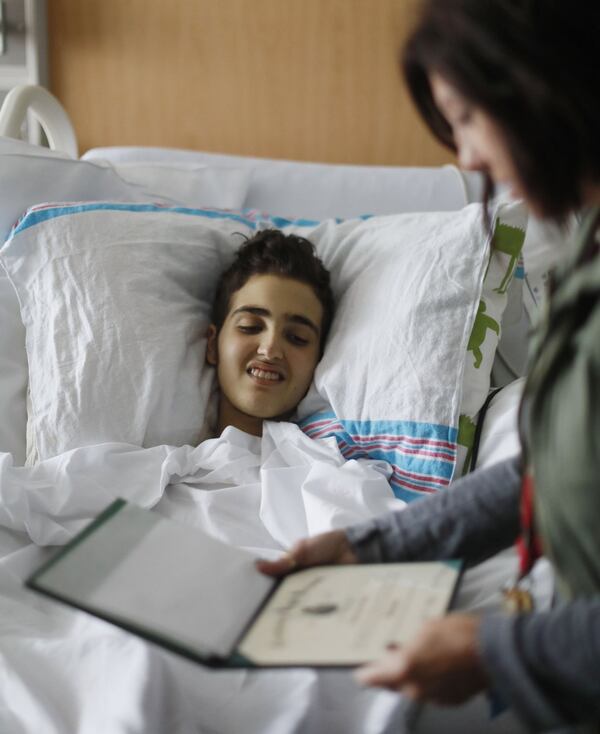 May 30, 2019 - Atlanta - Logan Droke gets a look at his high school diploma from Lori Pirtle, the hospital’s educational advocate for his unit. Pirtle has been working with Logan since he was 9 years old. Logan, 18, from Canton, facing his fourth battle with leukemia at Children’s Healthcare of Atlanta at Scottish Rite, wi to graduate from Creekview High School on Friday. Firefighters in two departments are rallying behind the teenager by raising money to help pay for treatments. Bob Andres / bandres@ajc.com