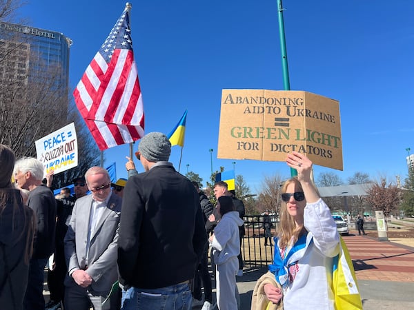 A protester holds up a sign that reads, "Abandoning aid to Ukraine = Green light for dictators" at Centennial Olympic Park. (Ashley Ahn for AJC)