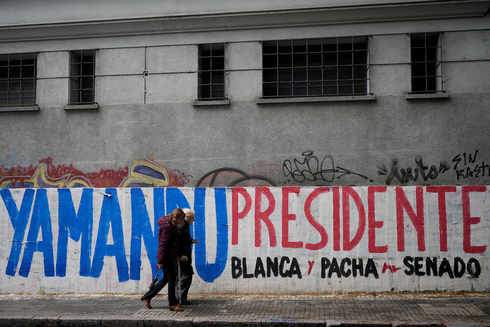 Pedestrians walk past a campaign mural promoting Frente Amplio presidential candidate Yamandu Orsi, ahead of Sunday's upcoming general election, in Montevideo, Uruguay, Friday, Oct. 25, 2024. (AP Photo/Natacha Pisarenko)