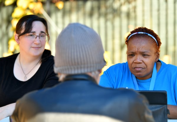 Tanya Davenport, right, is a support specialist with Intown Cares, a nonprofit that helps people in need.  Sitting with intern Chelsea Piccirilli, left, Davenport talks to a client at her pop-up resources desk, which is held every week behind Druid Hills Presbyterian Church beside a food pantry event. (PHOTO by Hyosub Shin / Hyosub.Shin@ajc.com)