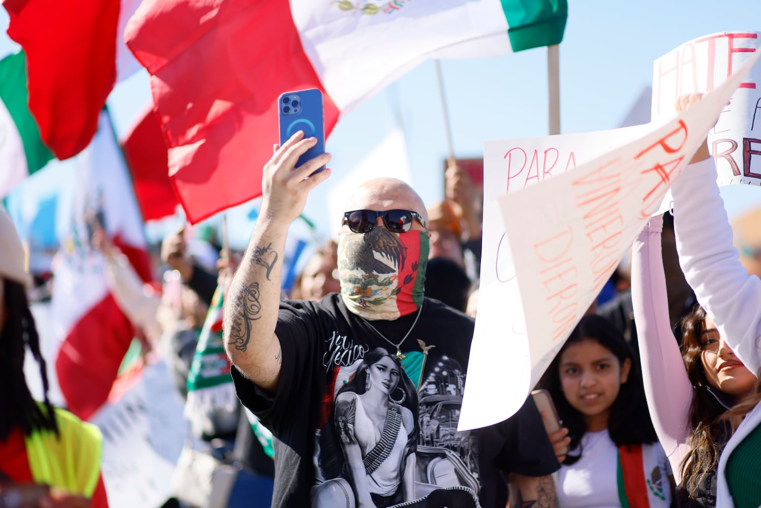 A person wearing a Mexican flag bandana records with his cell phone during a rally as protesters chant on the sidewalks of Plaza Fiesta on Saturday, February 1, 2025, to demonstrate in response to a recent immigration arrest in Georgia. 
(Miguel Martinez/ AJC)