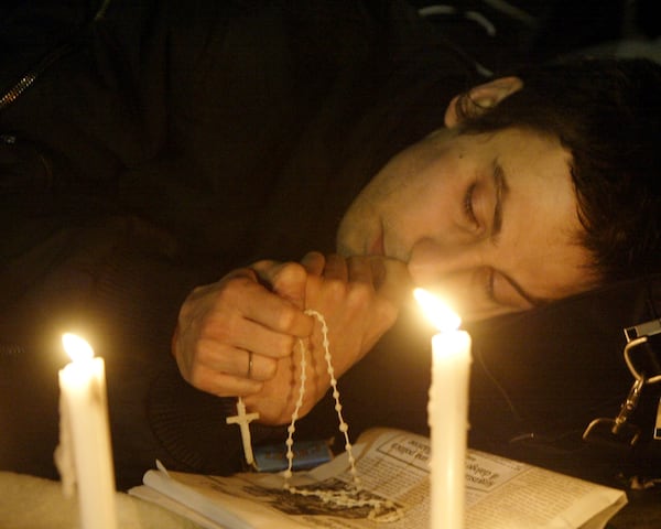 FILE- Faithful pray with a rosary after the death of Pope John Paul II was announced in St. Peter's Square at the Vatican, Saturday, April 2, 2005. (AP Photo/Luca Bruno, File)