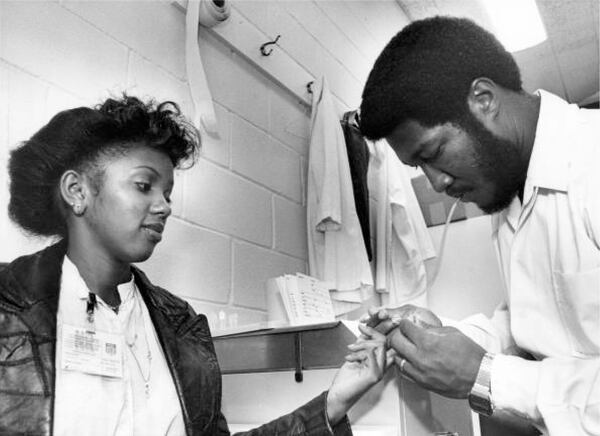 A patient at the Georgia Sickle Cell Foundation gives a sample of her blood to Phillip Oliver, a genetic counselor, so it can be tested in the lab for sickle cell anemia in this 1981 image. (Dwight Ross Jr. / AJC Archive at GSU Library AJCP302-032c)