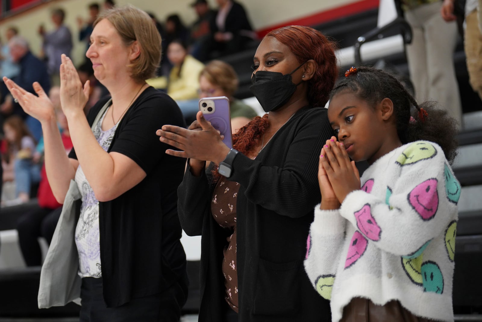 Mary Engidaw, center, and her daughter Harmony Hall, right, applaud during a Worthington High School choir concert in Worthington, Minn., on Monday, Oct. 21, 2024. (AP Photo/Jessie Wardarski)